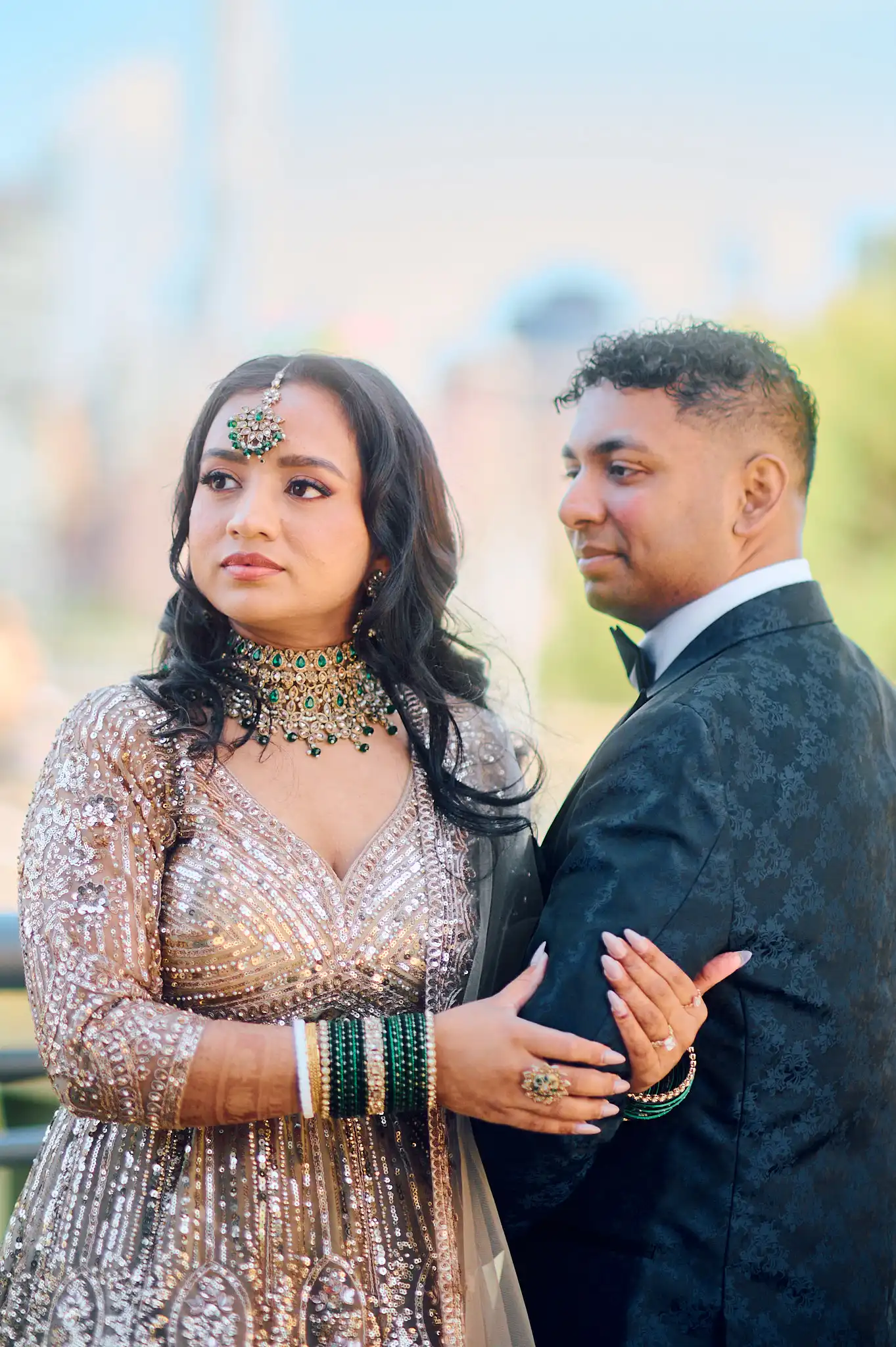 Bride and groom in yellow Haldi attire sharing a Maaza juice box in front of a marigold flower curtain